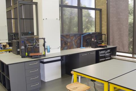 Variety of 3-D printers on a row of desks