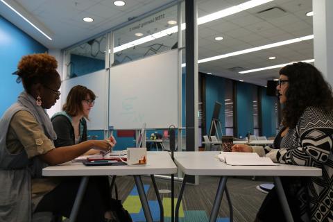 three students in conversation around a table