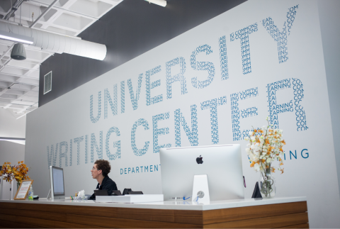 person at desk with UWC logo on wall behind them