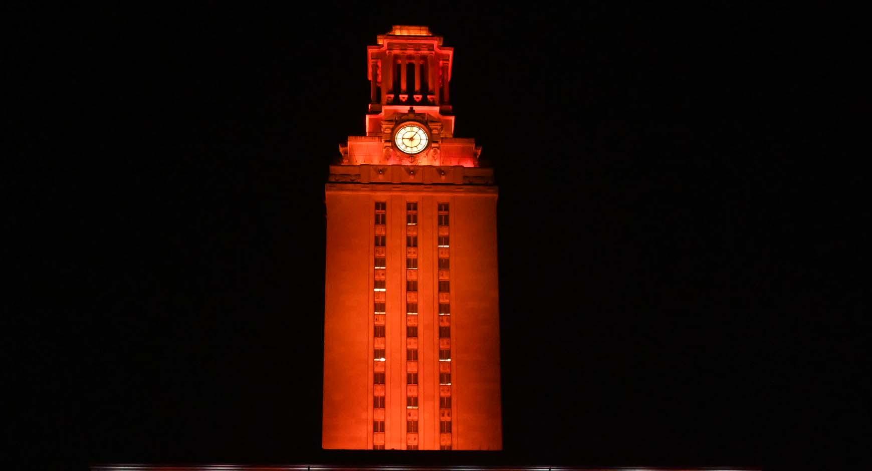 ut tower lit by orange light at night
