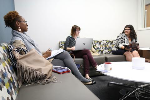 Three students conversing on couches