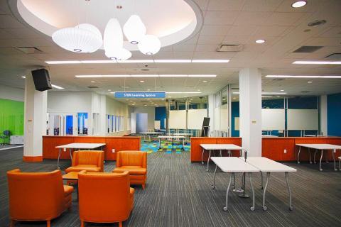 row of orange lobby chairs and white tables