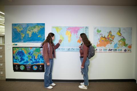 Two students discussing a map on the wall