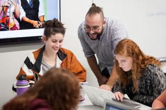 two students being helped by a smiling instructor