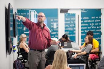 person in front of a monitor teaching to a group