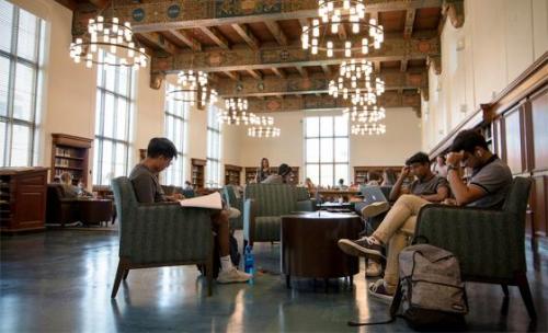 students sitting and studying in a large open library space