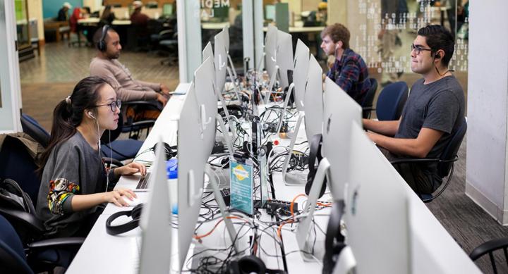 students sitting and working at a row of computers