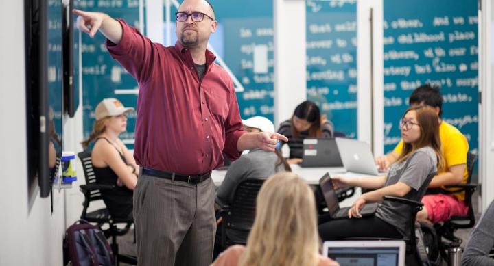 Person teaching in a with students and a chalkboard