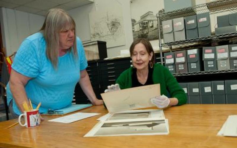 Area is a photo of the Alexander Architectural Archives area. Two women admire some documents at a table.